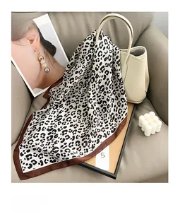 Close-up of leopard print silk scarf draped over an elegant cream leather handbag