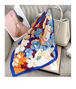 Détail d'un foulard en soie à motif floral élégamment drapé sur un sac en cuir beige