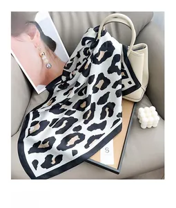 Leopard print silk scarf tied on a beige leather handbag in a stylish lifestyle setting