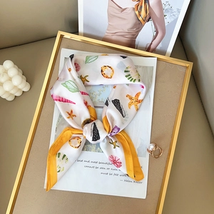 Elegant white silk scarf with yellow borders and ocean shell patterns on a gold frame
