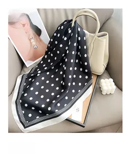Polka dot silk scarf elegantly draped on a beige handbag with a lifestyle setup