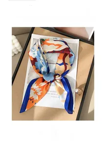 Détail d'un foulard en soie aux motifs floraux bleus et oranges sur un plateau