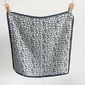 Detailed view of square silk scarf with black and white leopard print and black border