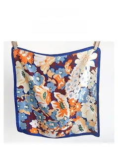 Détail d'un foulard en soie synthétique avec imprimé floral et couture de bord