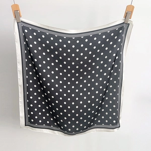 Detailed view of black and white polka dot silk scarf featuring classic checkered borders