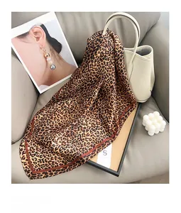 Detail of leopard print silk scarf tied on a white leather bucket bag in a lifestyle setting