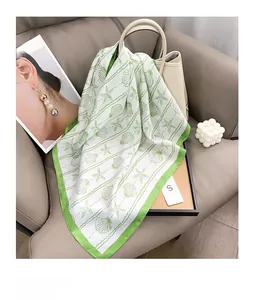 Detail of silk scarf with starfish print draped over a beige leather bag on a sofa