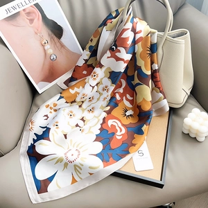 Détail d'un foulard en soie à fleurs sur un sac montrant la texture et les bordures