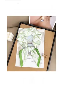Detailed view of marine print silk scarf with seashells and green wave borders