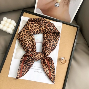 Fashionable leopard print silk scarf styled as a bow tie with elegant gold pearl ring accent