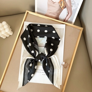 Hepburn style black and white polka dot silk scarf tied in a bow on a gold frame