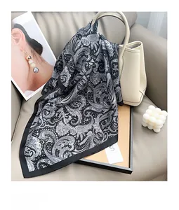 Detail of silk satin paisley scarf in black and white draped on a luxury leather handbag
