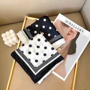 Classic black and white polka dot silk scarf duo displayed on a stylish golden tray