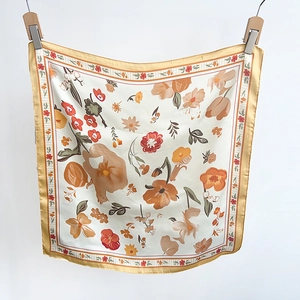 Detail view of smooth floral satin square scarf with yellow border hanging on a line