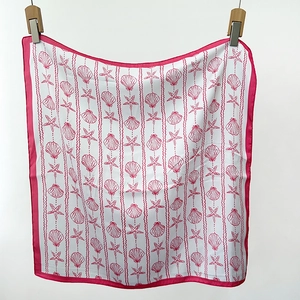Detail of pink seashell and starfish pattern on silk scarf with fuchsia border