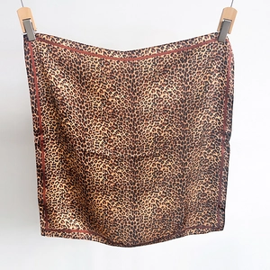 Detail view of leopard print silk scarf texture with professional hemmed edges