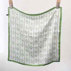 Detail view of square satin scarf with green seashell print and premium hemmed edges