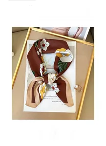 Détail d'un foulard en soie fleurie dans un plateau doré en tissu doux et soyeux