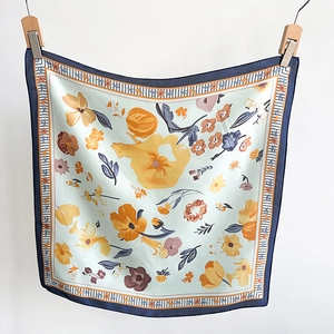 Detailed close-up of floral square silk scarf with mint green base and navy blue border