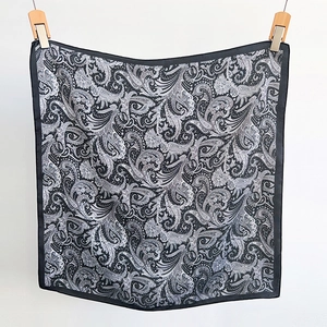 Detail of a square silk scarf with classic black and white paisley patterns on satin fabric