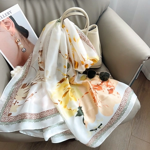 Close-up of floral silk scarf with yellow flowers draped on a grey leather sofa