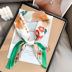 Elegant floral silk neck scarf with green border and orange blossoms in wood tray