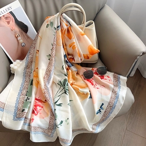 Detailed close-up of elegant floral print silk scarf draped over a cream-colored handbag