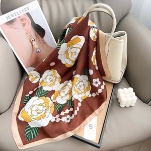 Foulard en soie marron à imprimé rose et chaîne de perles drapé sur un sac à main