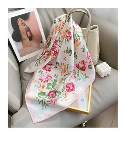 Dettaglio di uno scialle di seta bianco con stampa floreale drappeggiato su una borsa