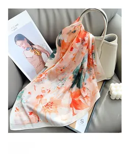 Detail view of floral silk scarf draped on a leather handbag in a modern setting