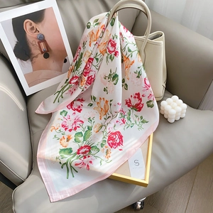 Elegante foulard di seta a fiori con bordi rosa drappeggiato su una borsa in pelle