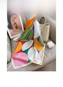 Detail of silk scarf with geometric patterns draped over a beige leather handbag