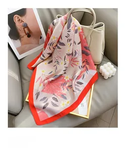 Détail d'un foulard en soie fleurie élégant posé sur un sac à main en cuir blanc