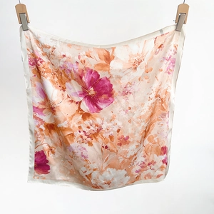 Detailed view of floral silk-like scarf with orange and pink printed patterns