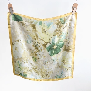 Detailed macro view of floral pattern silk scarf with yellow satin rolled edges and soft sheen