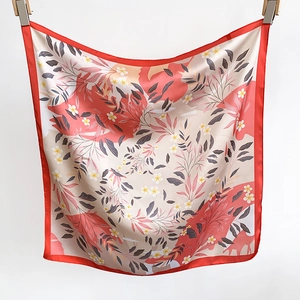 Détail d'un foulard en soie rouge et blanc avec des motifs de feuilles et fleurs jaunes