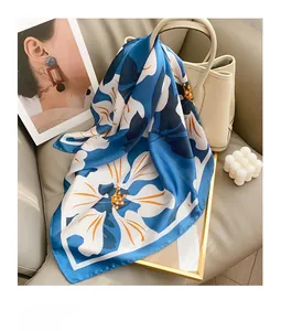 Floral print silk scarf draped over a bucket bag in a stylish lifestyle setting