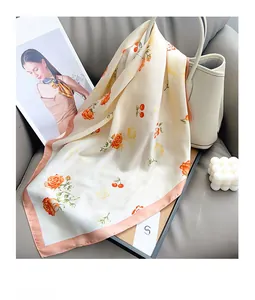 Detailed texture of floral silk scarf draped elegantly on a cream leather bucket bag