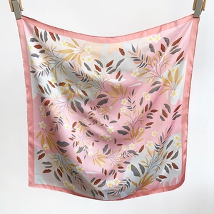 Vue détaillée d'un foulard carré en soie rose tendre aux motifs floraux et botaniques