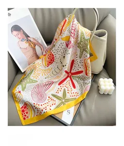 Détail du foulard en soie à imprimé d'étoiles de mer drapé sur un sac à main beige