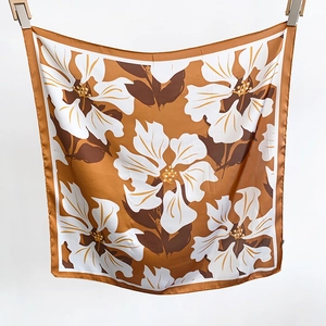 Detailed view of large square silk scarf featuring abstract floral patterns in ginger yellow