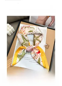 Vue détaillée d'un foulard en soie avec motif floral étoile de mer et bordure jaune