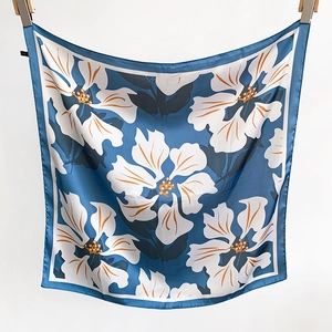 Detail of navy blue floral silk scarf with white hibiscus patterns and rolled edges
