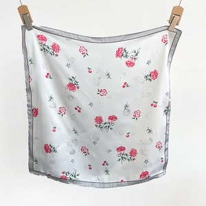 Detail of square silk scarf with red rose, cherry, and blue star prints on white fabric
