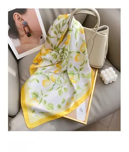 Vue détaillée d'un foulard en soie à imprimé citron drapé sur un sac à main en cuir beige chic