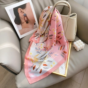 Élégant foulard en soie rose à motifs floraux disposé sur un canapé en cuir de luxe