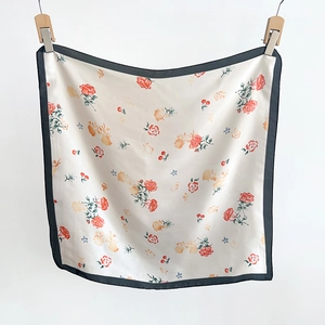 Detail of floral silk scarf featuring red roses and cherry patterns on cream base