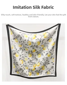 Détail d'un foulard carré soyeux avec imprimés citrons jaunes et bordures noires fines