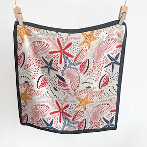 Détail du foulard en soie à imprimé coquillage et étoile de mer avec bordure noire