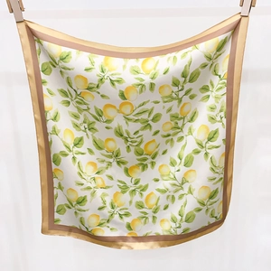 Détail d'un foulard carré en soie à imprimé citron avec des fruits jaunes et bordure en satin